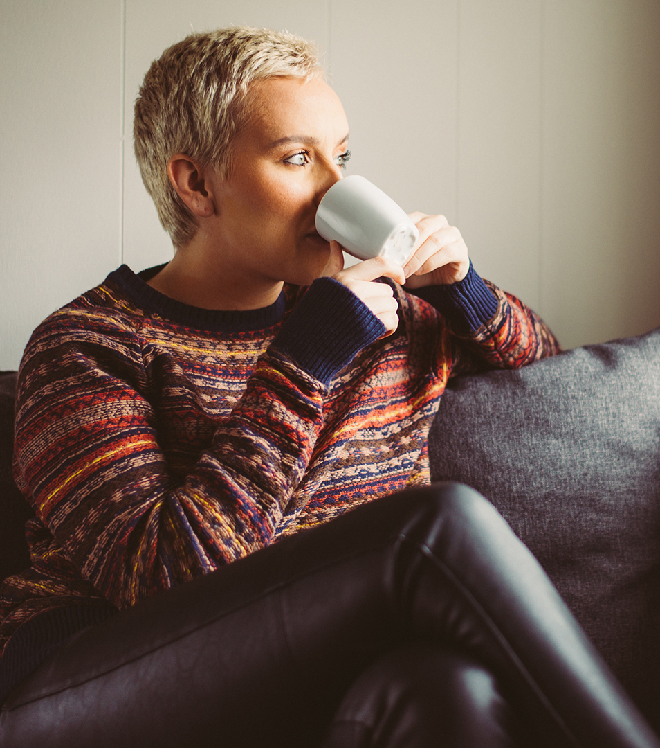 En person som sitter ner och dricker ut en mugg.