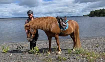 Titti med en häst på stranden.